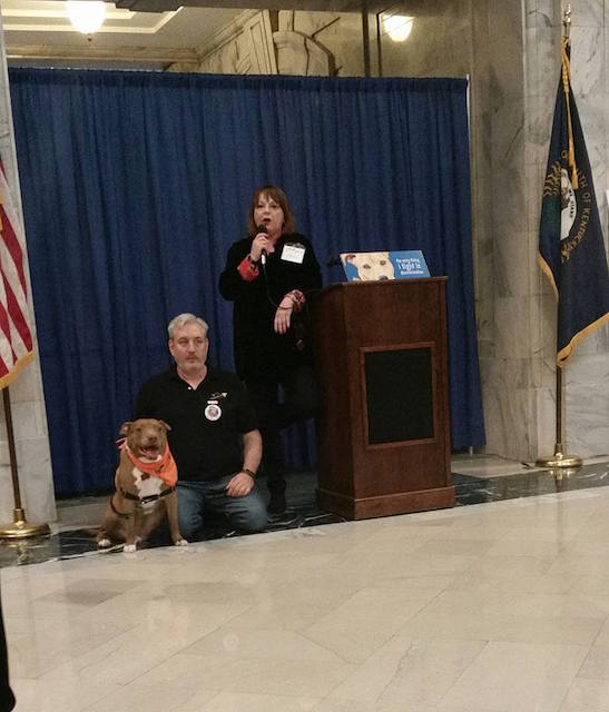 Rebecca Eaves speaking at Humane Lobby Day in Frankfort, KY with Thom Ham and Frodo, a victim of dogfighting.
