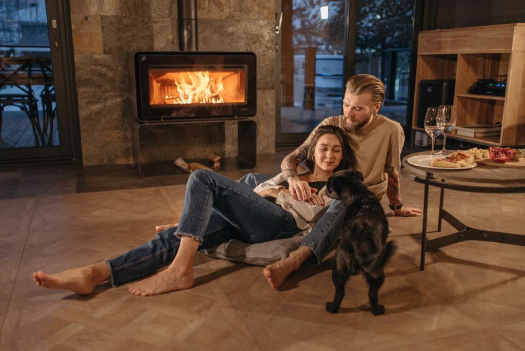couple snuggling near the fire with their dog